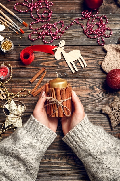 Mujer crea elegantes regalos navideños, decora una vela con canela