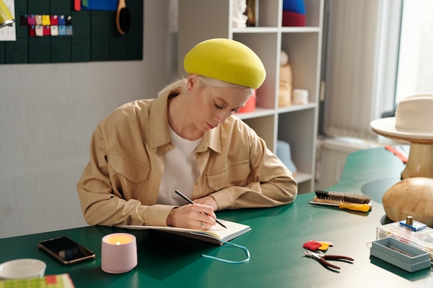 Mujer creativa joven dibujando bocetos de nuevos modelos en cuaderno