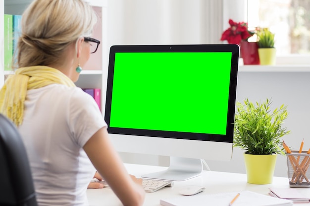 Mujer creativa joven que trabaja con la computadora en la oficina