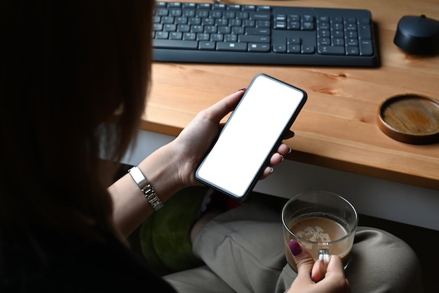 Mujer creativa sobre el hombro usando un teléfono inteligente en el lugar de trabajo