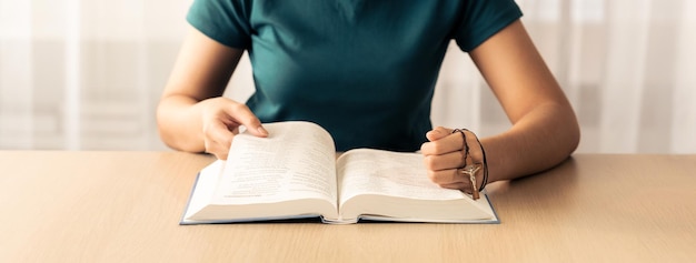 Mujer creyente lee la Biblia fielmente mientras sostiene la cruz Burgeoning