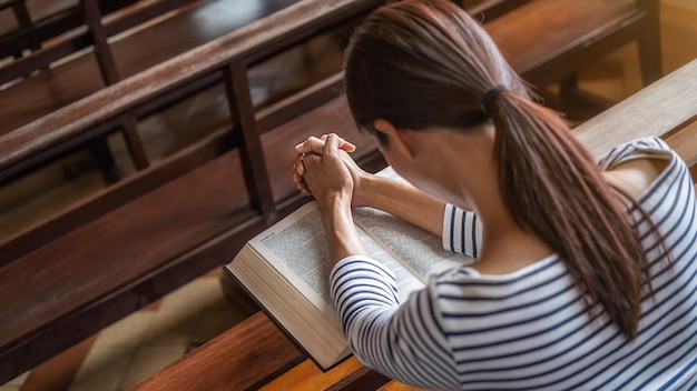 Foto mujer cristiana orando en la santa biblia en la iglesia pública