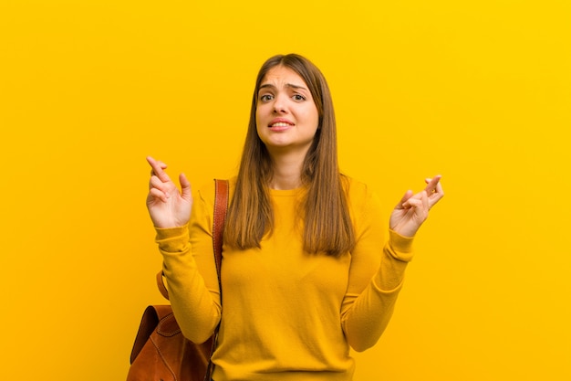 mujer cruzando los dedos ansiosamente y esperando buena suerte con una mirada preocupada