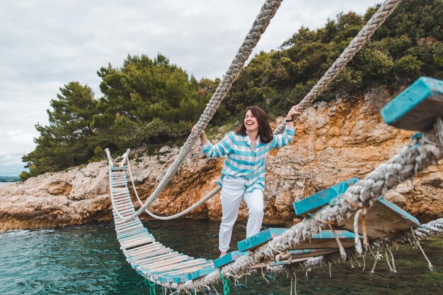 Mujer cruzando el puente colgante del mar en el horario de verano de fondo