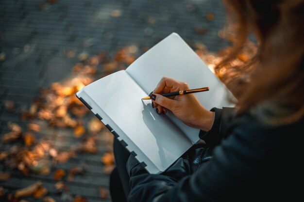 Foto mujer con cuaderno de cerca de una niña escribiendo en su diario en el parque una mujer escribe en un