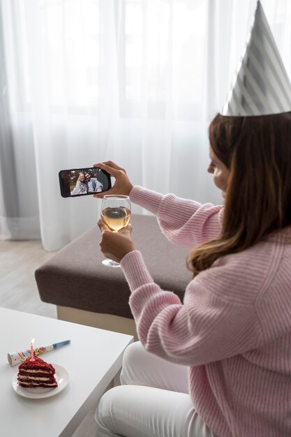 Mujer en cuarentena celebrando cumpleaños a través de smartphone