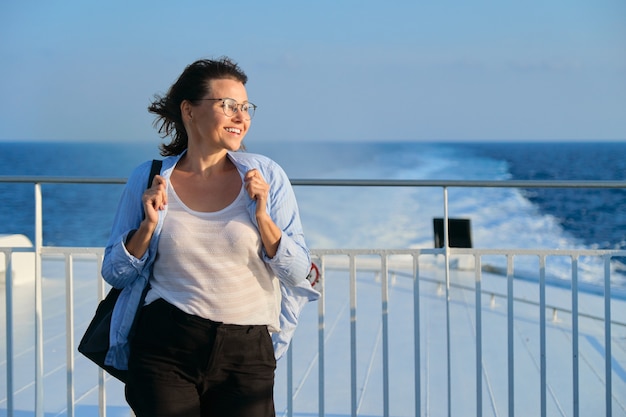 Mujer en la cubierta del ferry, mujer de pie con viento fuerte, disfrutando de los viajes por mar, puesta de sol en el mar, espacio de copia