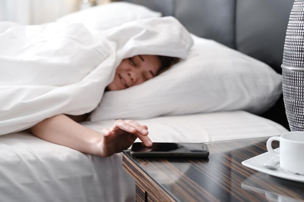 Mujer cubierta con una manta en la cama por la mañana