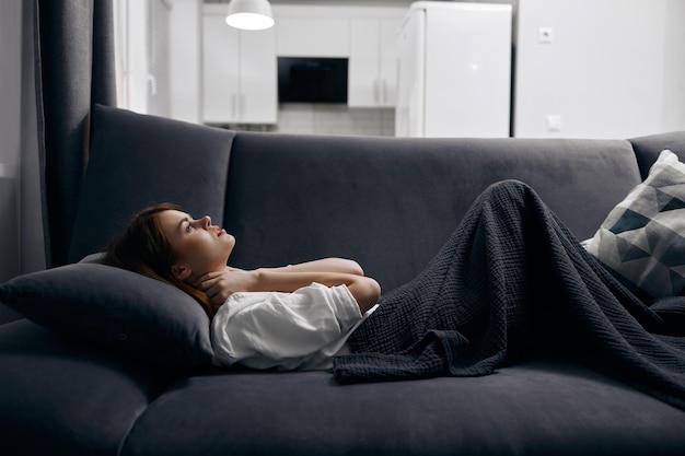 mujer cubierta con una manta está descansando acostada en el sofá