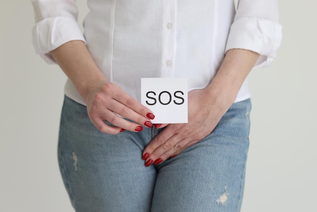 Foto la mujer cubre la ingle con la mano y muestra el mensaje sos en el estudio, la señora sufre un fuerte dolor en