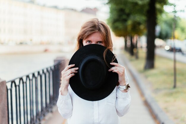 Mujer cubre la mitad de su rostro con un sombrero