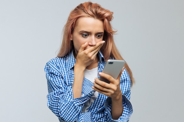 Mujer cubriendo la boca con la mano, mirando su teléfono