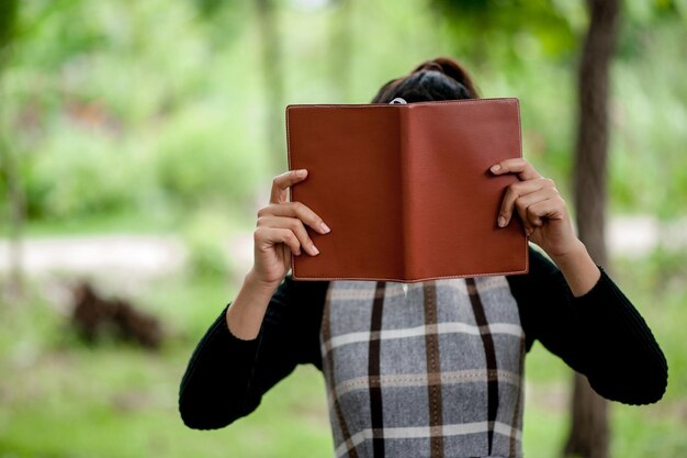 Foto mujer cubriendo la cara con un libro