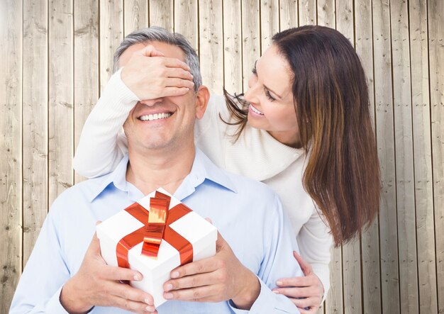 Mujer cubriendo los ojos del hombre mientras regala