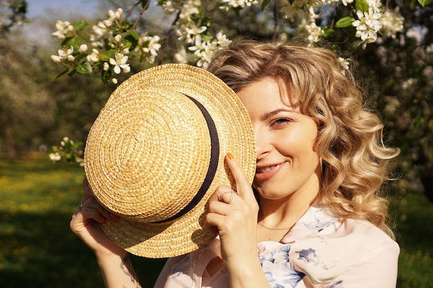 Mujer cubrió la mitad de la cara con un sombrero de paja - tiempo feliz en el jardín verde - primavera y verano