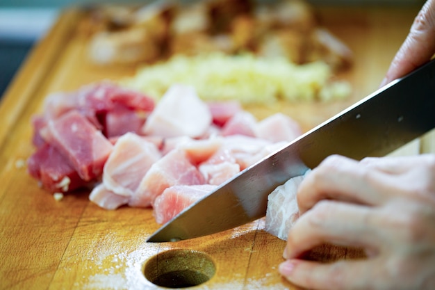 Mujer con un cuchillo para cortar la carne de cerdo para preparar la comida del almuerzo