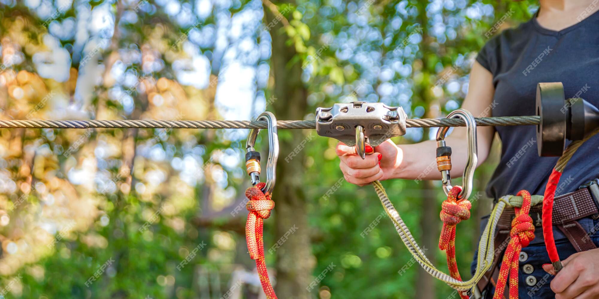 ir al trabajo A escala nacional granizo Mujer cuelga un mosquetón en una cuerda en un parque de aventuras en el  bosque. uso de material de escalada: mosquetón, cinturón, cuerda. banner  para publicidad, diseño o encabezado de sitio web 