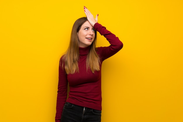 La mujer con cuello alto sobre una pared amarilla se ha dado cuenta de algo y pretende la solución.