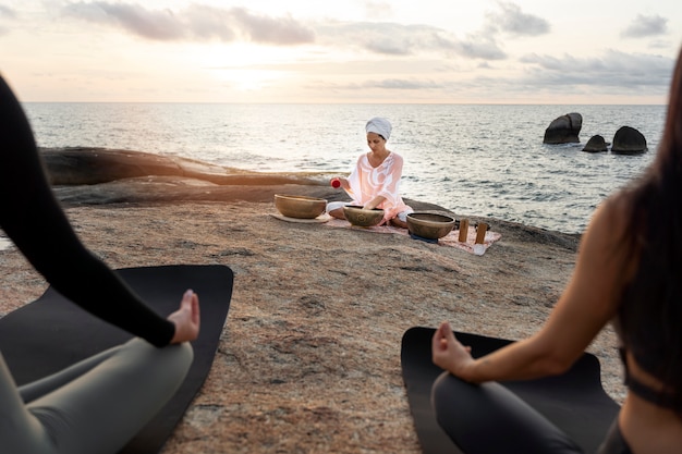 Foto mujer con cuencos cantores en la playa