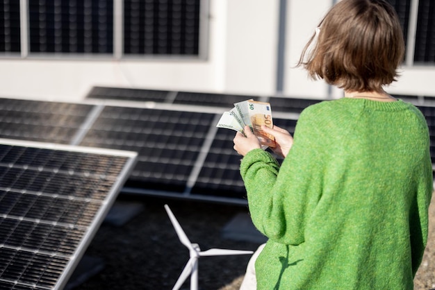 Mujer cuenta billetes en euros cerca de la planta de energía solar