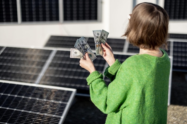 Foto mujer cuenta billetes en euros cerca de la planta de energía solar