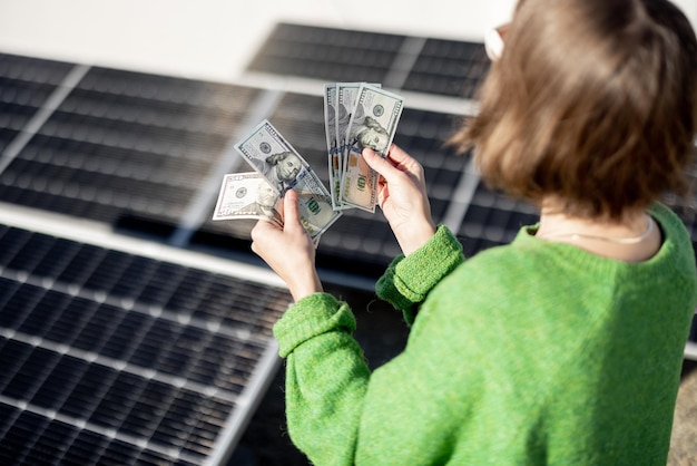 Mujer cuenta billetes en euros cerca de la planta de energía solar