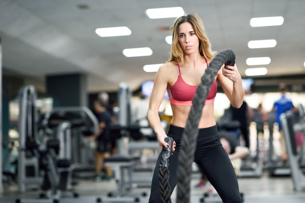 Mujer con cuerdas de batalla ejercicio en el gimnasio.