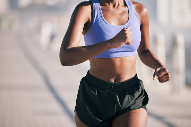 Mujer y cuerpo de primer plano corriendo al aire libre en el sol para la carrera de maratón rendimiento deportivo y acondicionamiento físico Entrenamiento cardio de corredora femenina y entrenamiento saludable de verano para energía acción rápida y ejercicio urbano