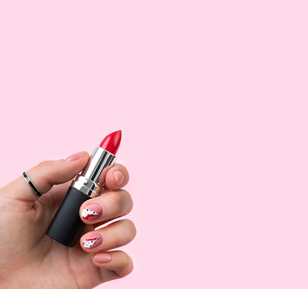 La mujer cuidada mano sosteniendo un lápiz labial rojo