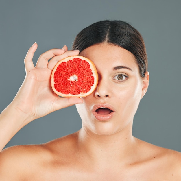 Mujer de cuidado de la piel con retrato de pomelo o cara de asombro para la salud, el bienestar, la estética o el producto facial Salud saludable de vitamina C o nutrición con lujo de belleza o comida en la mano del modelo en el estudio