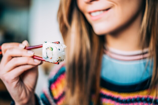 Mujer de cultivo comiendo sushi