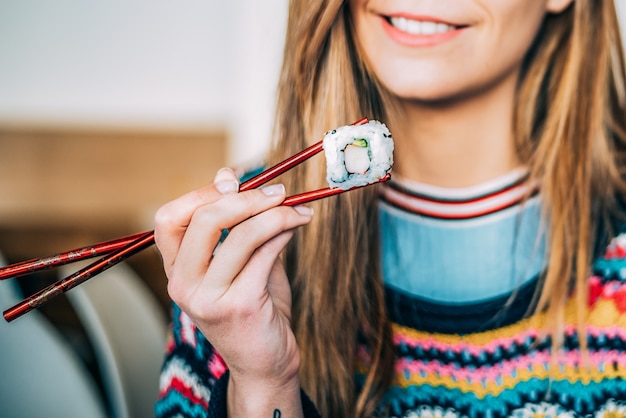 Mujer de cultivo comiendo sushi