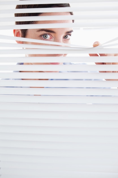 Foto mujer curiosa asomando por la ventana