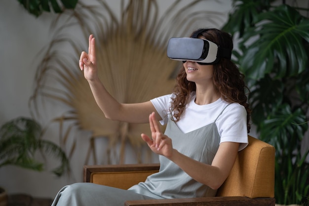 Mujer curiosa en casco vr interactuando con objetos en el mundo virtual probando gafas ar