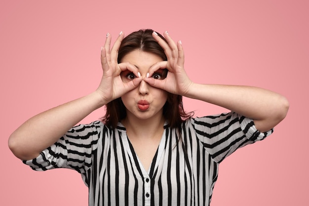 Mujer curiosa haciendo pucheros con los labios y gesticulando anteojos