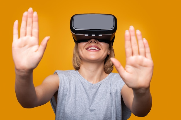 Mujer curiosa que se siente emocionada por la simulación de auriculares VR explorando la vida virtual haciendo gestos con las manos para tocar el mundo 3d