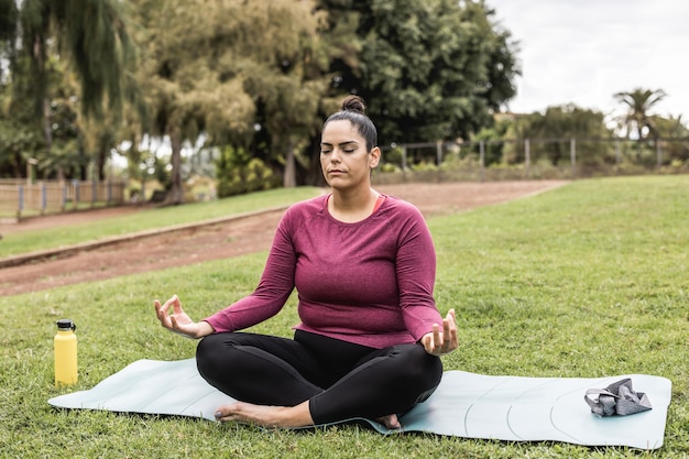 Mujer con curvas haciendo meditación de yoga al aire libre en el parque de la ciudad - Centrarse en la cara