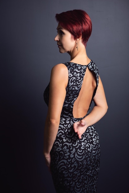 Una mujer con curvas en un vestido negro posa sobre un fondo oscuro Foto de moda