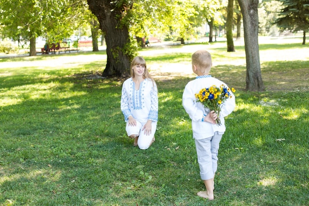 Una mujer le da un ramo de flores a un niño.