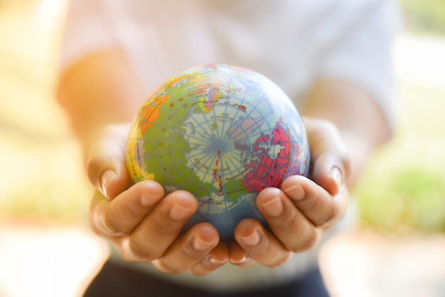 La mujer da sostener la bola del mundo en su mano con el fondo verde natural. Concepto del día mundial del medio ambiente.