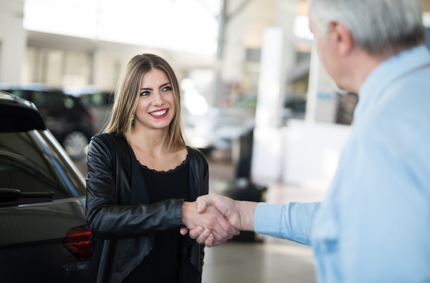 Mujer dando un apretón de manos para sellar el trato para su nuevo auto