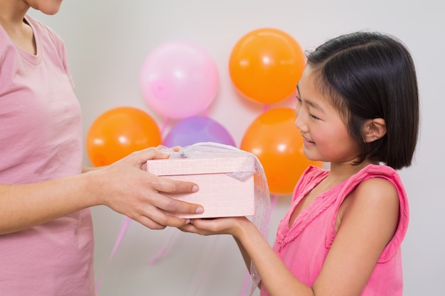 Mujer dando caja de regalo a una niña en una fiesta de cumpleaños