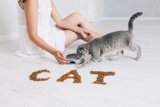 Mujer dando comida a gato