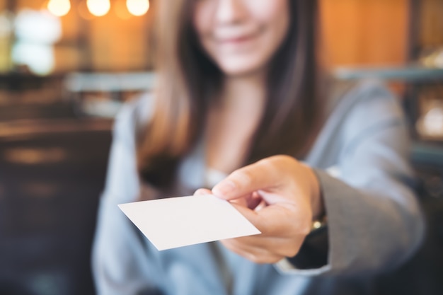 Foto mujer dando una tarjeta de negocios vacía