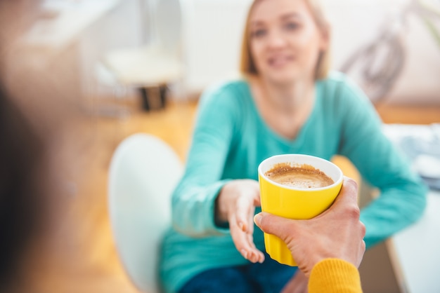 Mujer dando taza de café a su colega