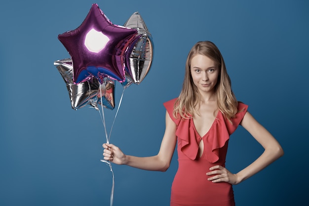 Mujer decidida con globos de estrellas en la pared azul