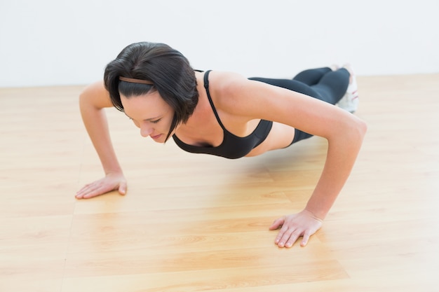 Mujer decidida haciendo flexiones en gimnasio