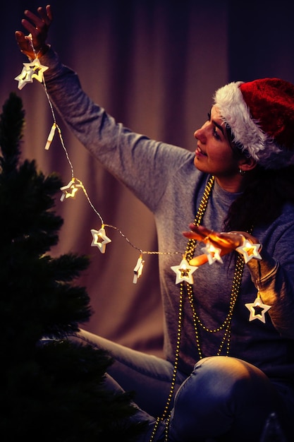 Foto mujer decora el árbol de año nuevo con una guirnalda en llamas