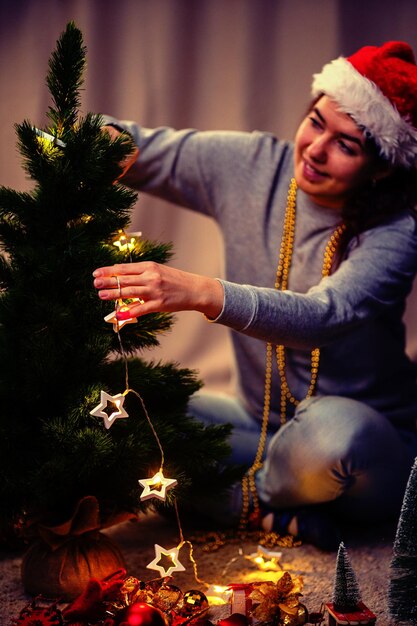 Foto mujer decora el árbol de año nuevo con una guirnalda en llamas