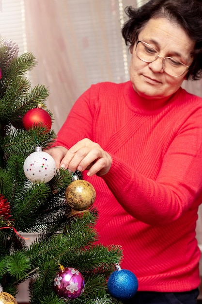 Una mujer decora un árbol de Navidad y Año Nuevo Preparación para Navidad y Año Nuevo